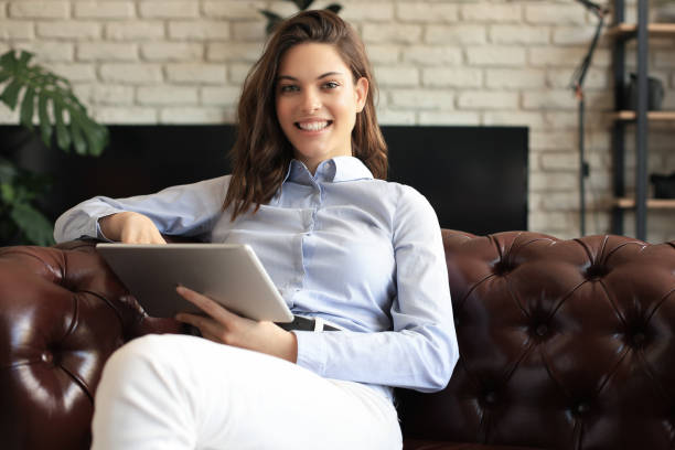 istock Young smiling woman with tablet pc on the sofa. 1253012816