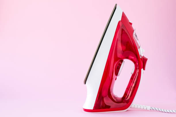 istock Red plastic iron on a pink background. Ironing devices, household concept. Template with copy space, empty place for text. 1253014667