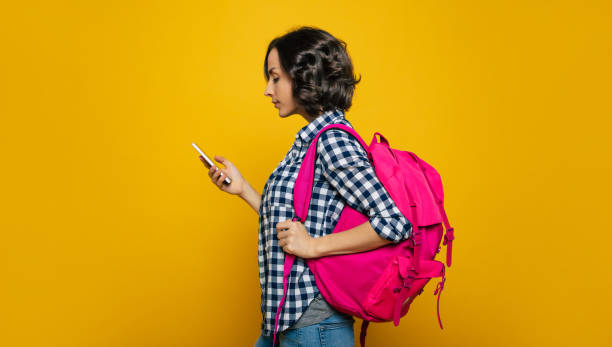 istock Checking my schedule! A half-length photo of a young student, dressed casually, with her cute pink backpack on her one shoulder, turned sideways to check her schedule on her phone. 1253015725
