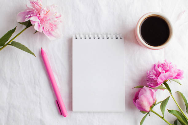 A morning Cup of coffee for Breakfast, an empty Notepad for your text or design, pink peony flowers. A woman's desktop.