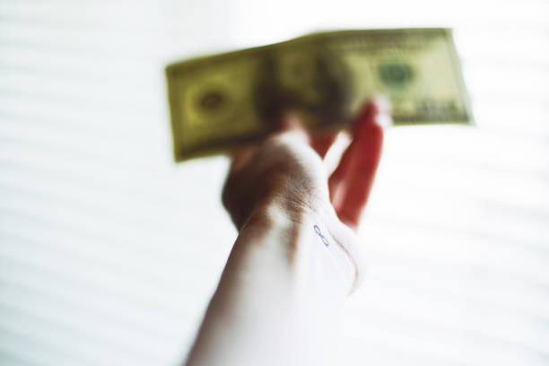 istock Tattoo infinity on the wrist. Blurred dollar bill in hand on a white shiny background 1253018416