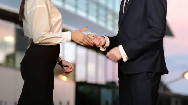 Photo of Businessman pays businesswoman in euros and they shake hands aft