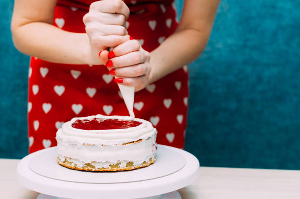 housewife applies the cream on the cake biscuit cake. Cake making process. Woman hands stock photo