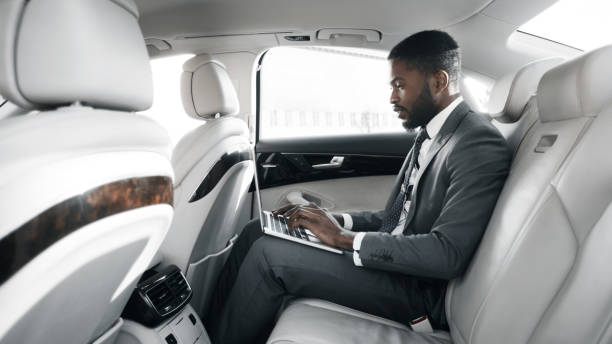 istock Black Businessman Using Laptop Working In Car During Ride, Panorama 1253021462