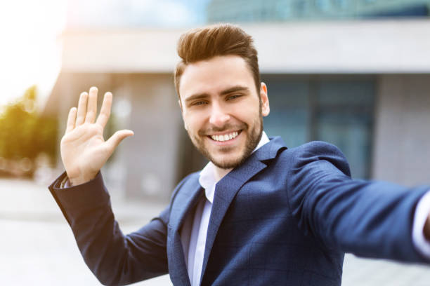 istock Cheerful entrepreneur waving his hand while taking selfie at downtown area 1253021537