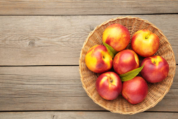 istock Nectarines in a basket on grey background with copy space 1253021538