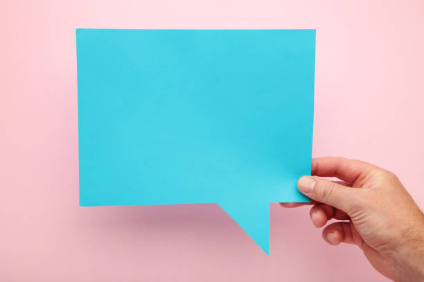 istock Hand holding an blue empty speech bubble on pink background 1253022671