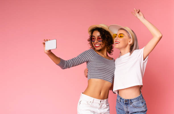 istock Two cheerful girlfriends in summer slothes taking selfie on smartphone together 1253023038
