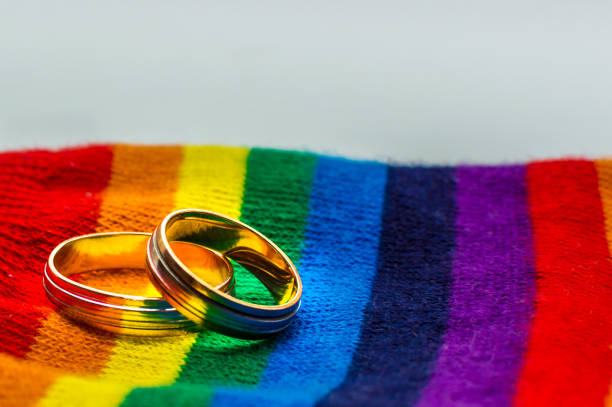 Two wedding rings on the fabric colors of the rainbow. Concept same-sex marriage. Two wedding rings on the fabric colors of the rainbow. Concept same-sex marriage. marriage equality stock pictures, royalty-free photos & images