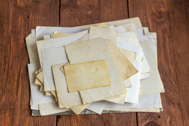 istock A stack of old yellowed photographs on an old wooden table. 1253024024