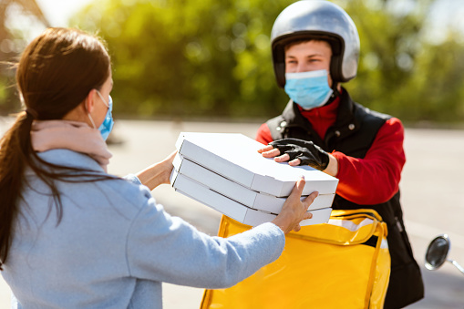 Pizza Delivery Concept. Courier Boy Giving Pizzeria Boxes To Customer, Wearing Protective Mask Standing On Street Outdoors. Selective Focus
