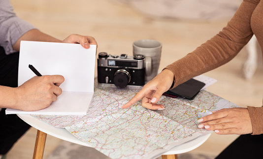 Travel Plan. Unrecognizable Spouses Pointing Fingers At Map Choosing Vacation Destination Sitting At Home. Cropped, Top-View