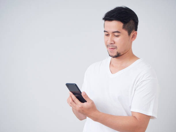 istock Young man with smartphone while standing on gray background. 1253028911