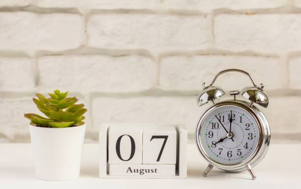 istock August 7 on a wooden calendar next to the alarm clock. Summer day, empty space for text.Calendar for August on a light background. 1253032133