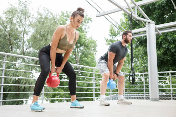 istock Athletic couple exercising with kettle bells  on a terrace 1253033108