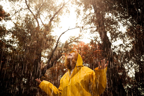 istock Happy young woman in raincoat during rain 1253033404