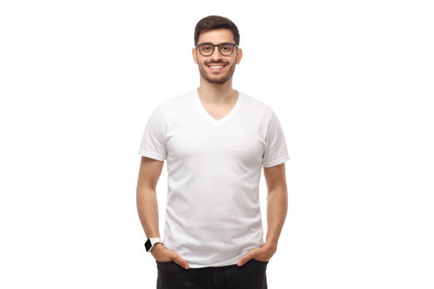 junger mann steht mit händen in taschen, trägt brille und leeres weißes tshirt mit kopierraum, isoliert auf studio-hintergrund - männliche figur stock-fotos und bilder