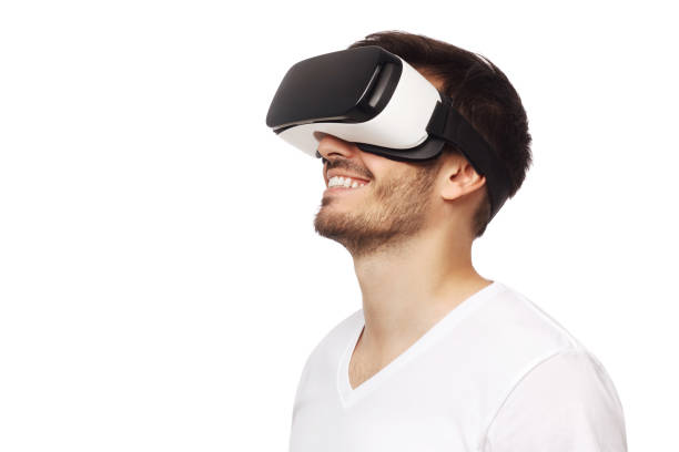 Young happy man smiling while enjoying and experiencing virtual reality with VR headset, isolated on white background