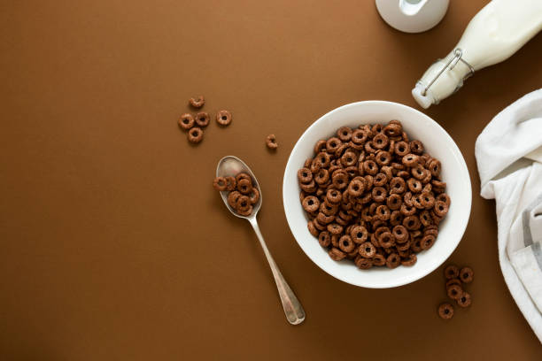 Breakfast for kind. Chocolate cereal rings in bowl brown background.