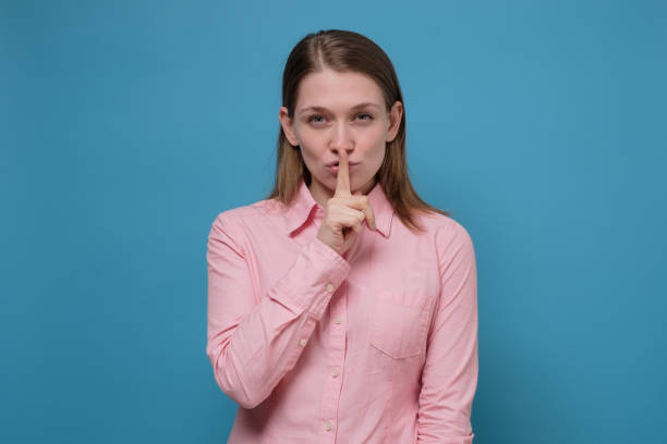 istock Young woman holding a finger on her lips showing silent gesture. 1253036983