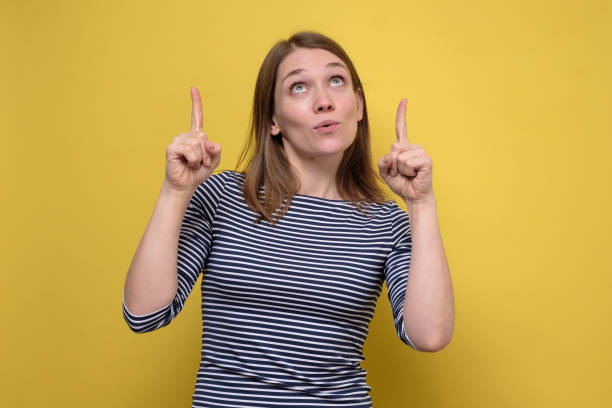 istock Successful friendly looking young woman pointing both index fingers up 1253037097