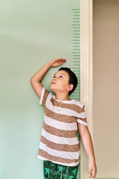 istock Child measuring his height on wall. He is growing up so fast. 1253040196