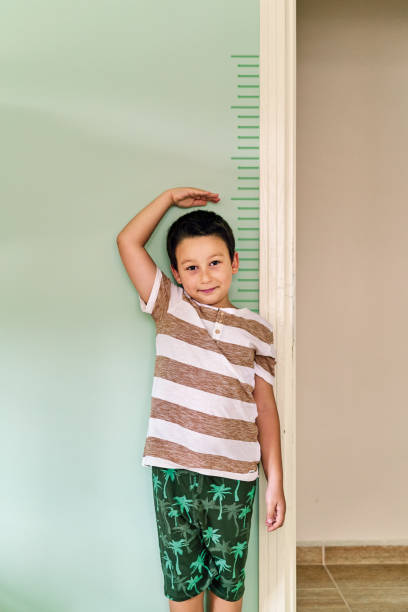 istock Child measuring his height on wall. He is growing up so fast. 1253040254