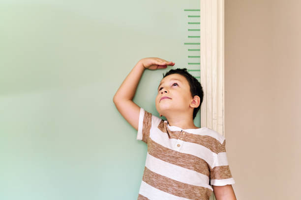 istock Child measuring his height on wall. He is growing up so fast. 1253040275