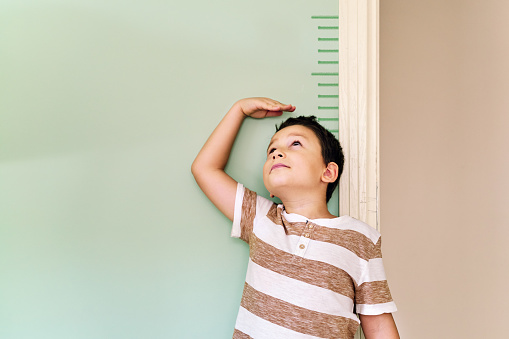 Child measuring his height on wall. He is growing up so fast.