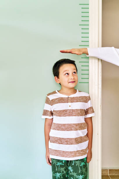 istock Mother measuring her son height on wall. He is growing up so fast. 1253040361