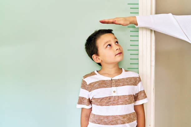 Mother measuring her son height on wall. He is growing up so fast.