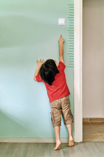 Child measuring his height on wall. He is growing up so fast.
