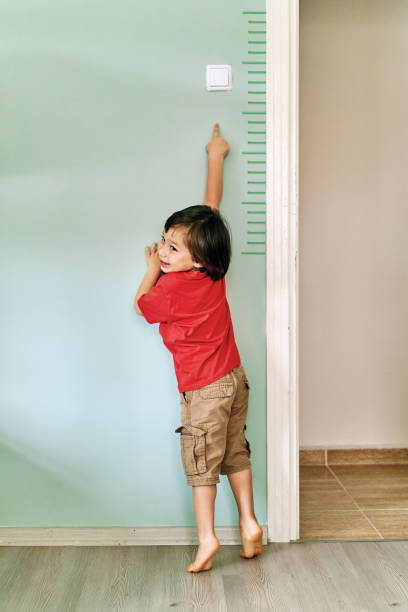 istock Child measuring his height on wall. He is growing up so fast. 1253041047