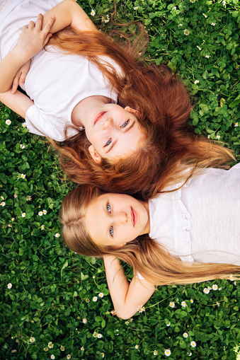 Two beautiful and young girls lie on the grass