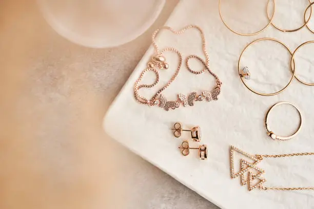 Luxury jewelry set of long earrings, pendant, butterfly bracelet, ring, stud earrings  on white marble plate. Women accessories. Closeup