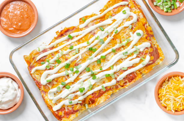 Keto ground beef enchiladas casserole Mexican food, homemade beef ground enchiladas in a ketogenic style with cheese tortillas in a glass oven dish on a white background with ingredients - directly above view enchilada stock pictures, royalty-free photos & images