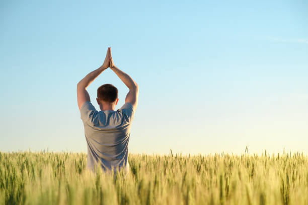 istock A man stands on a field in tall grass doing yoga during dawn. 1253049151