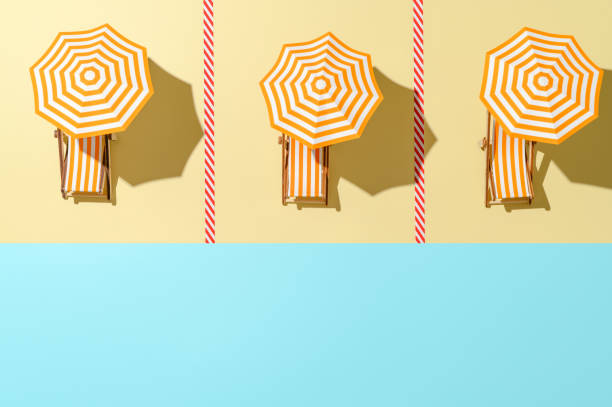 コロナウイルスのパンデミックの後にサンベッドと傘の時間を持つビーチのトップビュー。 - keeping above water ストックフォトと画像
