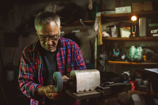 istock Professional senior craftsmen who in their old craft workshop - Repairs old things, constructs new products - The retiree enjoys working in his workshop 1253050336