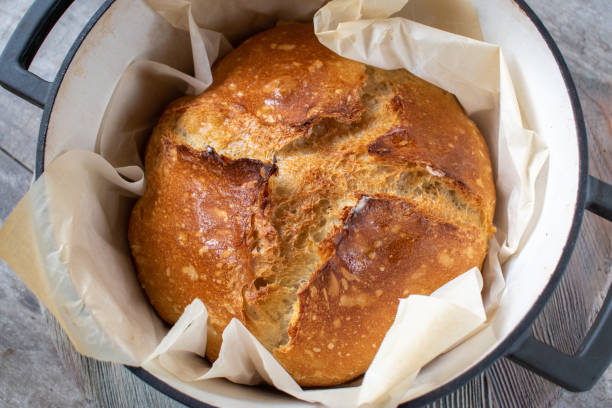 whole sourdough bread loaf with nice crust peaks in dutch oven stock photo