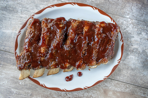 plated whole rack of beef ribs covered in barbecue sauce flat lay
