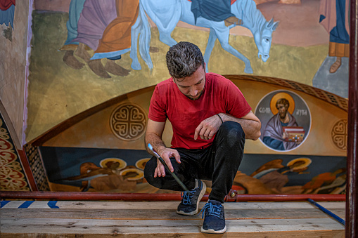 One male artist is painting frescoes in a church.