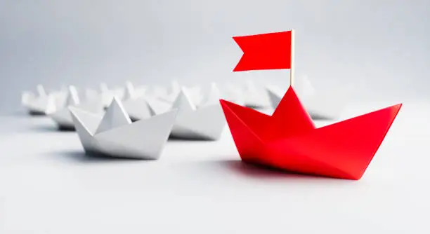 Group of white Paper Boats with red Leader on white background