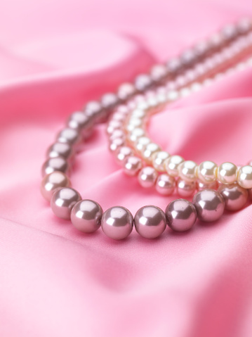 A closeup shot of a key pearl necklace worn by a Caucasian female.