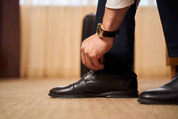 istock Man with classic watch tying shoelaces indoors 1253056749
