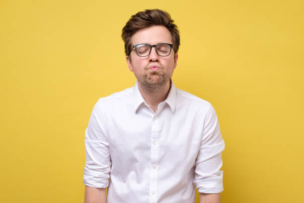 istock Handsome athletic guy with folded lips waiting for kiss, standing over yellow background. 1253059205