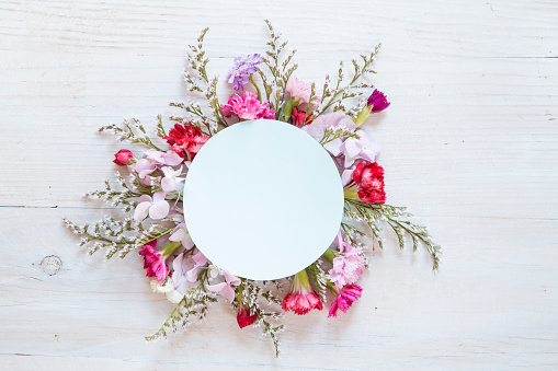 Floral circle with a blank note on white wooden  background