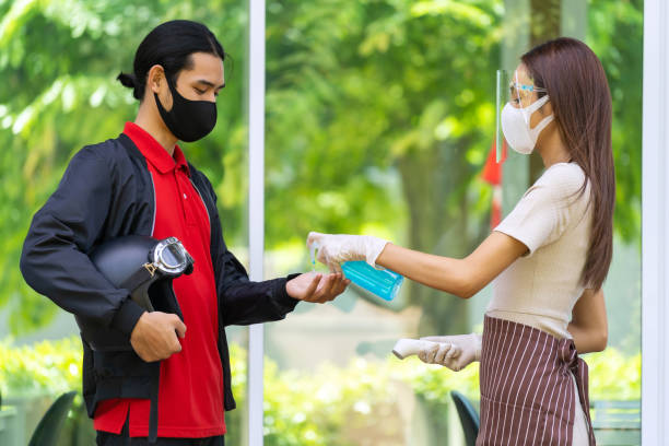istock Restaurant waitress push hand sanitizer gel for delivery man. 1253059342