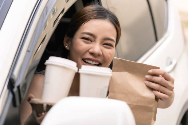 mujer asiática sosteniendo bolsa de comida de la unidad a través del restaurante de servicio - drive in restaurant fotografías e imágenes de stock