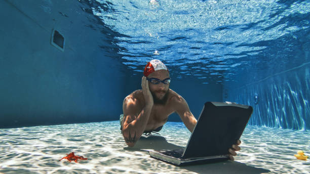 istock Workaholic man with laptop underwater: working addiction during summer vacations 1253063310